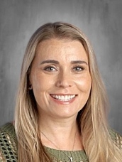 A smiling woman with long, straight blonde hair, wearing a green top, poses against a neutral background.