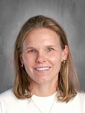 Headshot of a smiling woman with shoulder-length blonde hair, wearing a white shirt and simple jewelry.